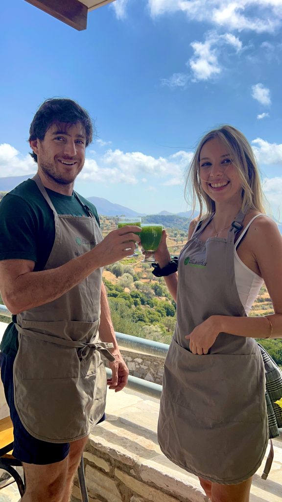 Guests enjoying detox smoothies at ELaiolithos with panoramic views of the Naxos highlands, embodying intentional and mindful luxury.