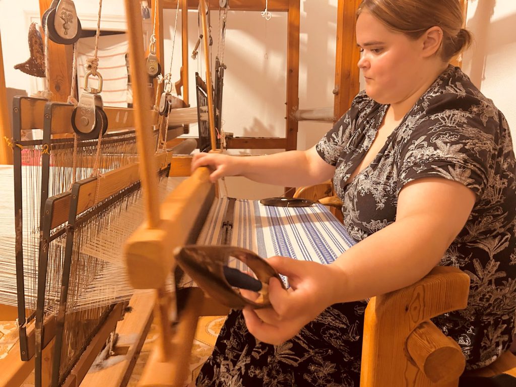 Guest working on a traditional loom at ELaiolithos, engaging with Naxos’ weaving heritage and local craftsmanship.